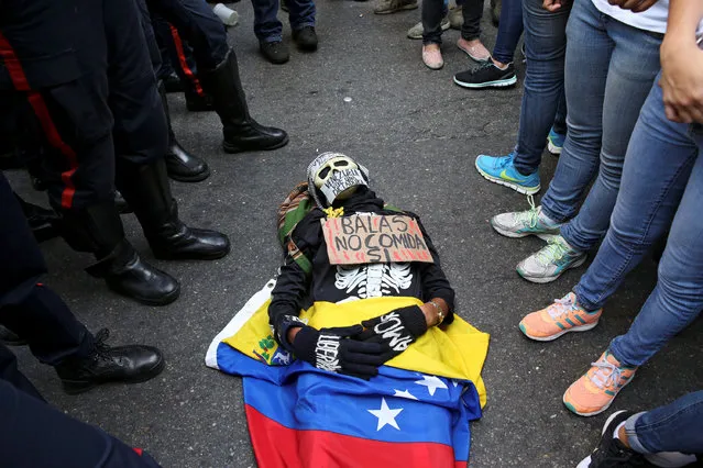 An opposition supporter wearing a costume and a placard that reads “Bullets no, food yes” lies on the floor in front of riot policemen during a rally against President Nicolas Maduro's government in Caracas, Venezuela November 10, 2016. (Photo by Carlos Garcia Rawlins/Reuters)