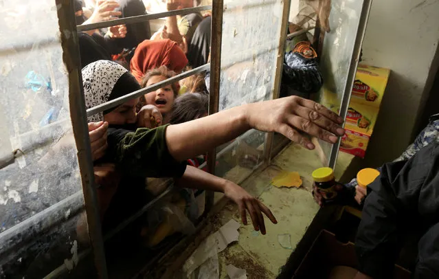 Women try to grab food supplies through a window at a school used as a food distribution point in Hammam Al-Alil, Iraq, November 13, 2016. (Photo by Zohra Bensemra/Reuters)