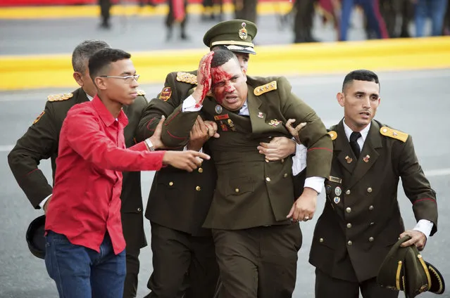 In this photo released by China's Xinhua News Agency, an uniformed official bleeds from the head following an incident during a speech by Venezuela's President Nicolas Maduro in Caracas, Venezuela, Saturday, August 4, 2018. Drones armed with explosives detonated near Venezuelan President Nicolas Maduro as he gave a speech to hundreds of soldiers in Caracas on Saturday but the socialist leader was unharmed, according to the government. (Photo by Xinhua News Agency via AP Photo)