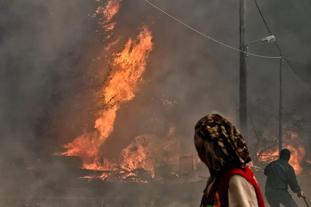Local residents look at the wildfire raging in the settlement of Irini, near the resort town of Loutraki, some 80 kilometres east of Athens, on July 17, 2023. Greek police on July 17, 2023 arrested a man suspected of starting an ongoing wildfire near Athens fuelled by a heatwave and strong winds, firefighters said. “Police carried out the arrest of a foreigner who allegedly caused the fire” in Kouvaras, around 50 kilometres (30 miles) southeast of Athens, said fire service spokesman Yannis Artopios. (Photo by Valerie Gache/AFP Photo)