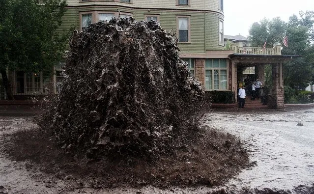 A geyser of floodwater shoots out of a sewer in Manitou Springs, Colorado, on September 12, 2013. The National Weather Service warned of an “extremely dangerous and life-threatening situation” throughout the region; at least three people have died as a result of the flooding. (Photo by Michael Ciaglo/The Gazette)