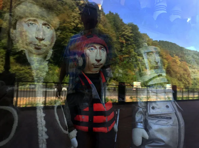 People walk past a souvenir shop displaying the dolls of Russian President Vladimir Putin at the embankment of the Mzymta river at Roza Khutor Mountain Resort, in Krasnaya Polyana on September 13, 2018, outside Sochi. President Vladimir Putin on Thursday visited Russia's largest-ever military drills in eastern Siberia, where he said Moscow planned to strengthen the country's armed forces. (Photo by Alexander Nemenov/AFP Photo)