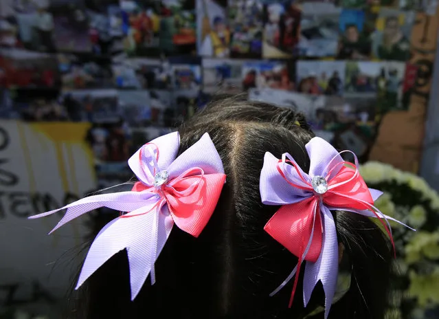 A girl looks at pictures of victims and the rescue efforts affixed to the wall surrounding the site at Alvaro Obregon 286, where 49 died when their office building collapsed in last year's 7.1 magnitude earthquake, in Mexico City, Wednesday, September 19, 2018. Across the city, memorials were held at sites where hundreds perished in the September 19, 2017 quake. (Photo by Rebecca BlackwellAP Photo)