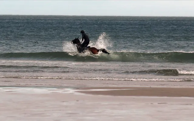 A man rides a horse at Bamburgh beach, following the easing of lockdown restrictions, Bamburgh, Northumberland, Britain on March 29, 2021. (Photo by Lee Smith/Reuters)