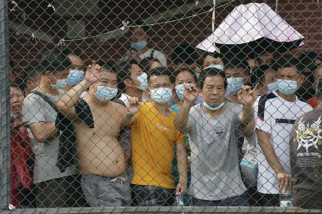 Residents wait in line for the coronavirus test in a district in Guangzhou in southern China's Guangdong province on Sunday, May 30, 2021. The southern Chinese city of Guangzhou shut down a neighborhood and ordered residents to stay home Saturday to be tested for the coronavirus following an upsurge in infections that has rattled authorities. (Photo by AP Photo/Stringer)