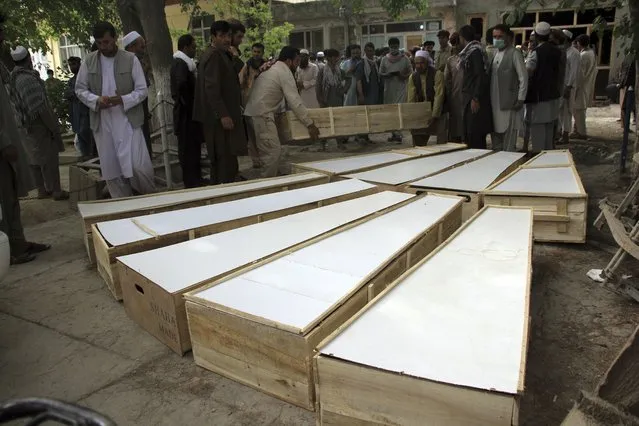 The coffins of the victims in Tuesday's attack are placed on the ground at a hospital in northern Baghlan province, Afghanistan, Wednesday, June 9, 2021. Workers of the HALO Trust de-mining organization were attacked on Tuesday night by the armed gunmen. (Photo by Mehrab Ibrahimi/AP Photo)