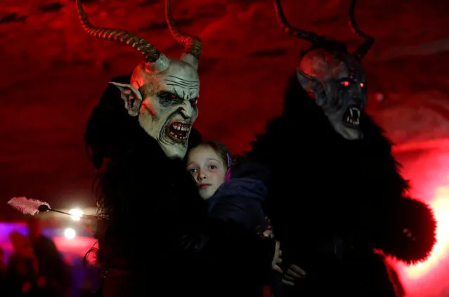 A man dressed as a devil embraces a child as part of a tradition to determine if she had behaved well during the past year, inside of a sandstone cave in the village of Svitava near the town of Cvikov, Czech Republic on November 26, 2018. (Photo by David W. Cerny/Reuters)