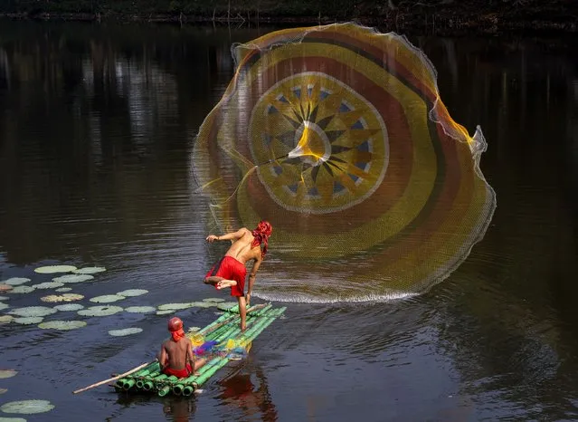 These fishermen create a colourful display as they throw out nets to catch fish on a lake in Bogor, West Java, Indonesia on September 26, 2023. (Photo by Lisdiyanto Suhardjo/Solent News & Photo Agency)