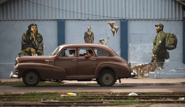 A vintage car drives by a mural showing Cuba's former leader Fidel Castro, national hero Jose Marti and revolutionary leader Che Guevara in Havana, August 2009. (Photo by Desmond Boylan/Reuters)