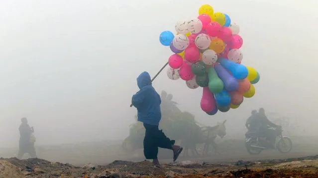 A Pakistani balloon vendor walks through a cold and foggy morning in Lahore on December 17, 2013. Ongoing foggy weather in Punjab and other parts of the country has badly affected flight and rail schedules. (Photo by Arif Ali/AFP Photo)