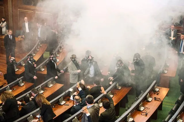 Kosovo police officers weeraing  gas masks inspect the parliament, after tear gas was launched by opposition lawmakers, disrupting the first parliamentary session of the year on February 19, 2016 in Pristina. Angry over a government deal with Serbia and demanding snap elections, the united opposition has effectively blocked parliamentary proceedings since October with their tear gas protests. (Photo by Armend Nimani/AFP Photo)