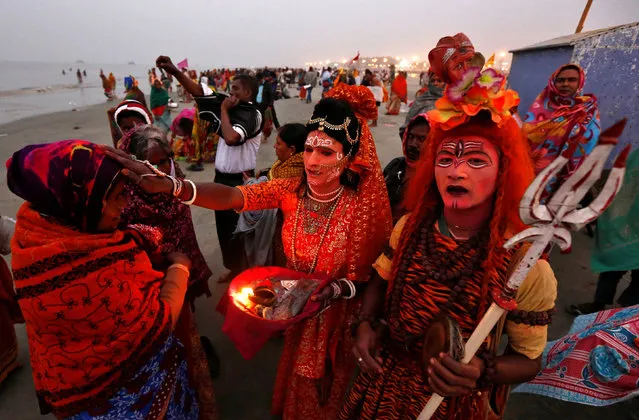 Two Indian men dressed as Hindu Lord Shiva (R) and Goddess Parvati (C) give blessings to a pilgrim at the confluence of the river Ganges and the Bay of Bengal, ahead of the “Makar Sankranti” festival at Sagar island, south of Kolkata, India January 13, 2017. (Photo by Rupak De Chowdhuri/Reuters)