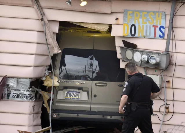 A police officer investigates a vehicle that crashed into the Better-Maid Donut shop, Wednesday, April 15, 2015, in Pittsburgh. Police didn't immediately release the names of the customers or the driver, but say one customer was pinned against a wall and another hurt her ankle. Police say the driver will be cited after apparently driving too fast and losing control shortly after 7 a.m. (Photo by Darrell Sapp/Pittsburgh Post-Gazette via AP Photo)