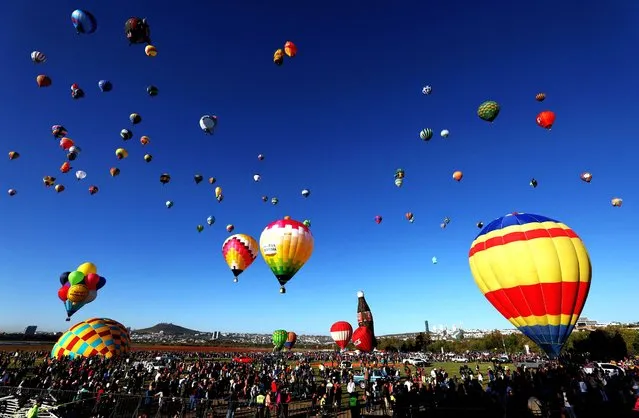 A group of people watch as hot air balloons rise during the 21st International Hot Air Balloon Festival in Leon, Guanajuato state, Mexico on November 17, 2023. (Photo by Ulises Ruiz/AFP Photo)