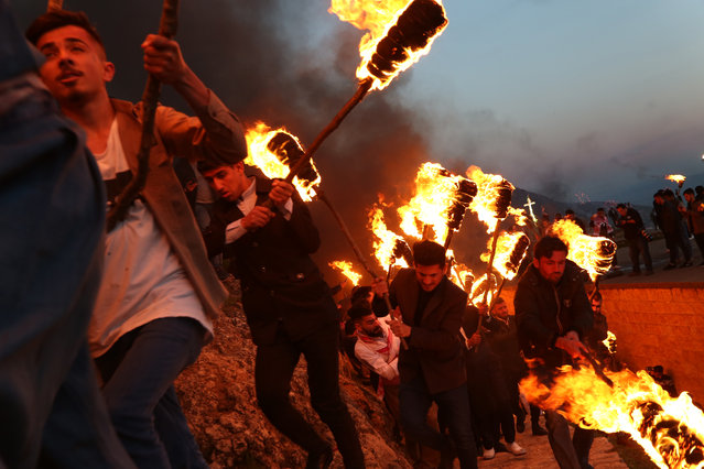 People participate in a torch procession during celebrations of the Kurdish New Year Nowruz (Also known as Newroz) in Akre, Aqrah City in Duhok, Kurdistan Region, northern Iraq, 20 March 2019. The Persian New Year Nowruz which has been celebrated for at least 3,000 years is the most revered celebration in the greater Persian world, which includes the countries of Iran, Afghanistan, Azerbaijan, Turkey, and portions of western China and northern Iraq. (Photo by Gailan Haji/EPA/EFE)