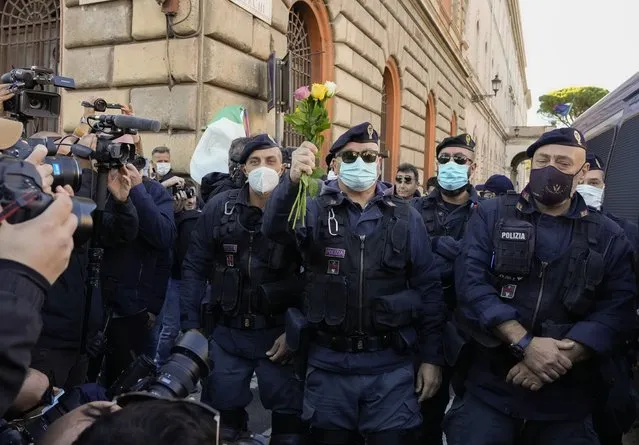 Demonstrators bring flowers to police officers, Friday, October 15, 2021, at Rome's Circus Maximus during a protest against a new anti COVID-19 measure requiring all workers to show a health pass to enter their place of employment. Police were out in force, schools ended classes early and embassies issued warnings of possible violence amid concerns that the anti-vaccination demonstrations could turn violent, as they did in Rome last weekend. (Photo by Gregorio Borgia/AP Photo)