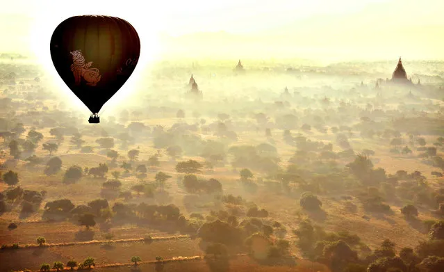 A hot air balloon provides a view of the temples as it hovers over Bagan in Myanmar on February 4, 2014. Between the 11th and 13th centuries, Bagan in Mandalay province in Myanmar was the kingdom's capital, one of the most important centres for learning in Asia, if not the world. (Photo by Ye Aung Thu/AFP Photo)
