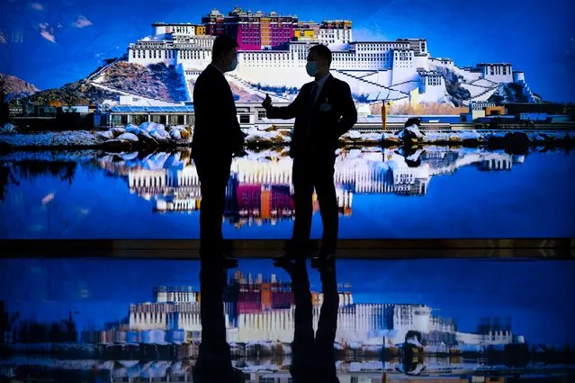 Attendees stand in front of a photo mural of the Potala Palace as they talk before a promotional event for Tibet at the Ministry of Foreign Affairs in Beijing, Wednesday, October 20, 2021. (Photo by Mark Schiefelbein/AP Photo)
