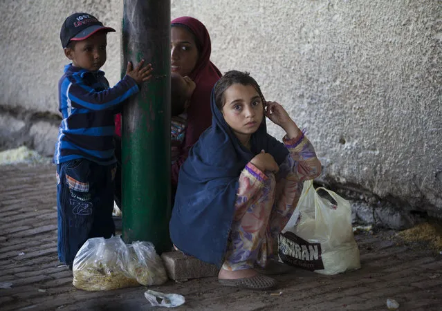 A Pakistani family waits for more food donations at a distribution center in the Barri Imam shrine in Islamabad, Pakistan, Thursday, April 23, 2015. People who visit shrines and pray that their wishes are fulfilled usually offer food to be distributed to the poor. Hundreds of poor families receive free food daily at the shrine. (Photo by B. K. Bangash/AP Photo)