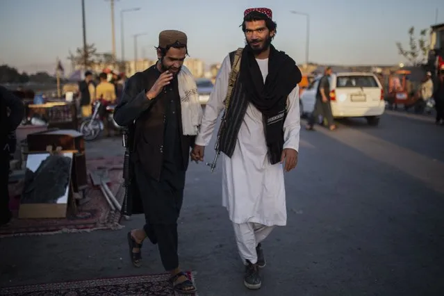 Taliban fighters walk through a market in Kabul, Afghanistan, Tuesday, October 12, 2021. (Photo by Ahmad Halabisaz/AP Photo)