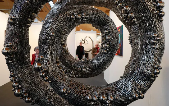 Visitors are seen through the work of art in stainless steel and marbel “Lucid Dream” by Indonesian artist Liechennay on display at the international trade fair “art Karlsruhe” in Rheinstetten near Karlsruhe, Germany, 16 February 2017. The “International Fair for Classical Modern and Contemporary Art” is taking place from 16 to 19 February in Rheinstetten. (Photo by Ronald Wittek/EPA)