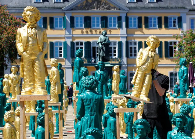 A Ludwig van Beethoven sculpture overlooks the Muensterplatz square as a worker sets up one of hundreds of Beethoven plastic sculptures designed by German conceptual artist Ottmar Hoerl to mark the 250th birth anniversary of German composer, who was born in the city, in Bonn, Germany May 15, 2019. (Photo by Wolfgang Rattay/Reuters)