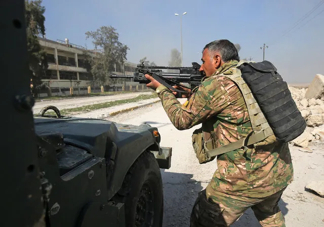 A member of the Iraqi forces aims his weapon on February 23, 2017, as they advance towards Mosul airport on the southern edge of the jihadist stronghold prior to entering the airport compound for the first time since the Islamic State group overran the region in 2014. Backed by jets, gunships and drones, forces blitzed their way across open areas south of Mosul and entered the airport compound, apparently meeting limited resistance but strafing the area for suspected snipers. (Photo by Ahmad Al-Rubaye/AFP Photo)
