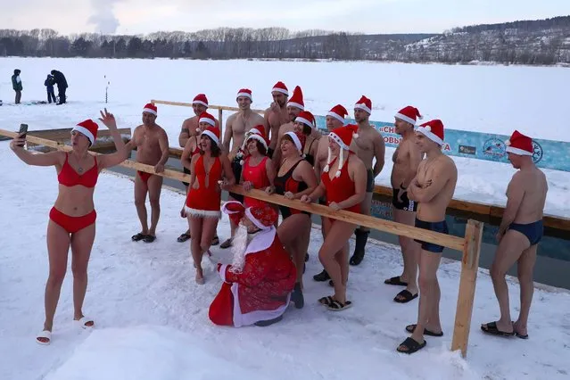 Members of the Snegiri (Bullfinches) winter swimming club pose for a group photo before having a swim in Lake Krasnoye in Kemerovo, Russia on December 12, 2021. (Photo by Maxim Kiselev/TASS)