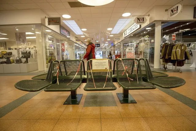 A woman walks past cordoned-off benches in a shopping centre in Freital, Saxony, Germany, Tuesday, December 28, 2021. Saxony has the lowest vaccination rate among Germany’s 16 federal states, and one of the highest numbers of COVID-19 cases. It also has seen angry and aggressive anti-vaccine protests in recent weeks. (Photo by Daniel Schaefer/dpa via AP Photo)