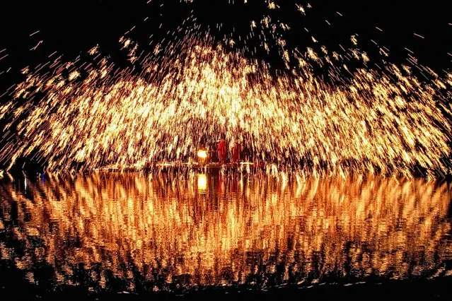 This photo taken on April 8, 2024 shows sparks created by molten iron being splashed during the Zhuang Song Festival, also known as “San Yue San” celebrated by ethnic minorities in Liuzhou, in southwestern China's Guangxi region. (Photo by AFP Photo/China Stringer Network)