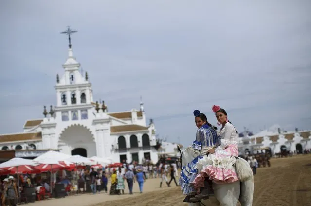 Pilgrims smile as they ride a horse in front of the shrine of El Rocio in Almonte, southern Spain May 24, 2015. (Photo by Marcelo del Pozo/Reuters)