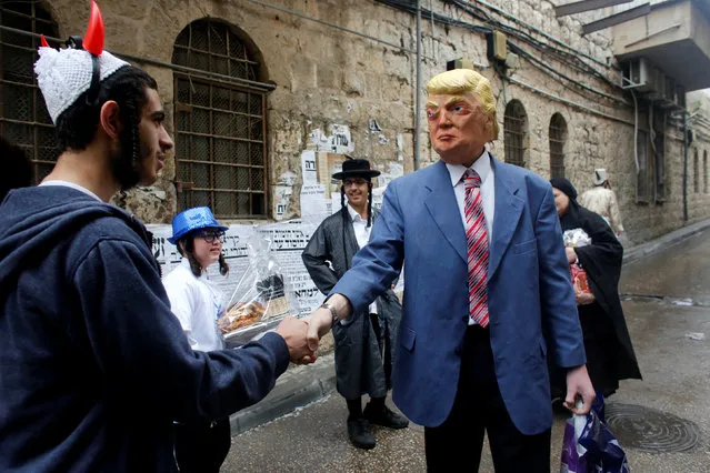 A person wearing a costume of U.S. President Donald Trump shakes hands with an ultra-Orthodox Jewish man during an annual parade marking the Jewish holiday of Purim, in Jerusalem March 13, 2017. (Photo by Nir Elias/Reuters)