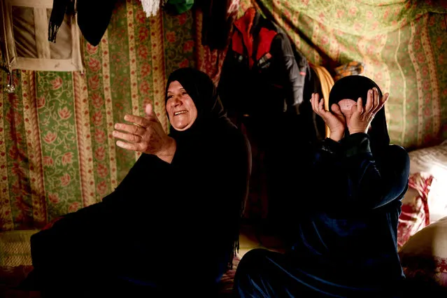 Samira Ouda Faris, left, and Fawzia Khalil Brahim laugh and cry on March 21, 2016, as they recount the day when they heard Iraqi forces had wrested control of their home city of Ramadi from Islamic State group militants. The women and their families, including 11 children, live in a small tent in a camp for displaced people in the nearby town of Habbaniyah. Nearly all of Ramadi's population of 1 million remains displaced months after the city's recapture because of the vast destruction wreaked by months of fighting there. (Photo by Maya Alleruzzo/AP Photo)