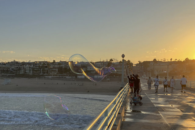 A man creates giant soap suds bubbles at dawn Monday, September 5, on the Manhattan Beach Pier in Manhattan Beach, Calif., as a severe heat wave gripped the state. Most of California's 39 million people are facing sweltering weather. (Photo by John Antczak/AP Photo)