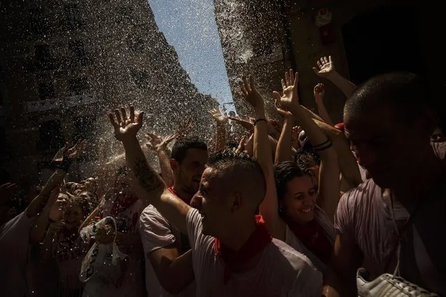 Revelers are sprayed with water as they celebrate during the launch of the “Chupinazo” rocket, to celebrate the official opening of the 2015 San Fermin fiestas in Pamplona, Spain, Monday, July 6, 2015. (Photo by Daniel Ochoa de Olza/AP Photo)
