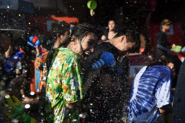 A woman reacts to being soaked in water during Songkran, or the Thai New Year, celebrations on Khaosan Road in Bangkok on April 14, 2017. (Photo by Lillian Suwanrumpha/AFP Photo)