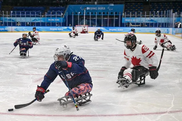 USA's Josh Pauls (C) controls the puck against Canada's Antoine Lehoux in the ice hockey preliminary round match between Canada and the US during the Beijing 2022 Winter Paralympic Games in Beijing on March 5, 2022. (Photo by Mohd Rasfan/AFP Photo)