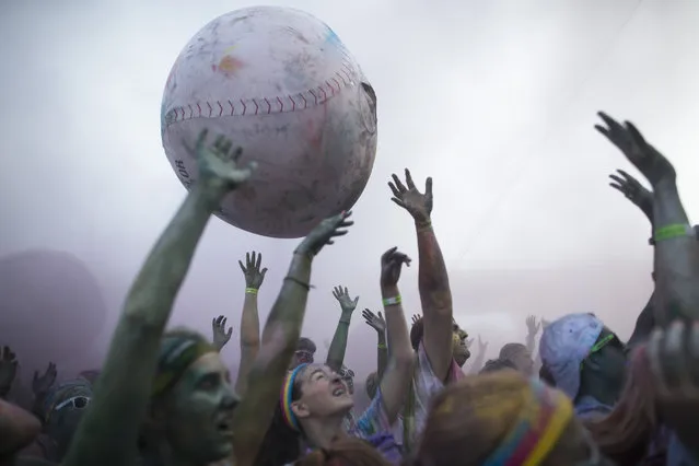 Runners play with a giant inflated baseball as they frolic in a haze of colored powder in Sawyer Point Park after completing The Color Run All-Star 5K as part of the All-Star Baseball game festivities, Saturday, July 11, 2015, in Cincinnati. (Photo by John Minchillo/AP Photo)