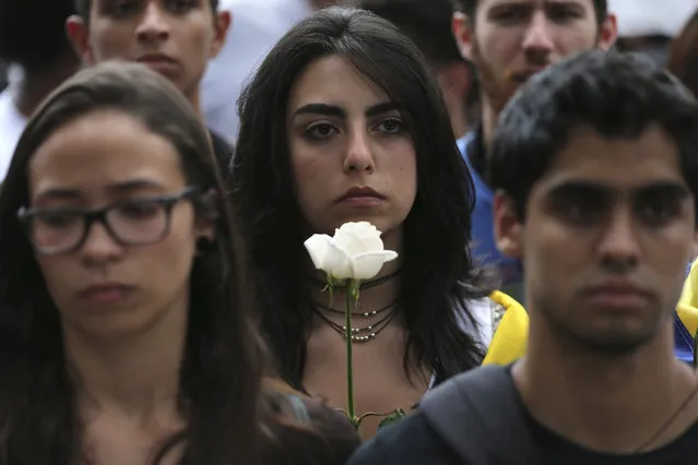 A protester carries a white flower during a silent protest in homage to the at least 20 people killed in unrest generated after the nation's Supreme Court stripped congress of its last powers, a decision it later reversed, during a march to the Venezuelan Episcopal Conference in Caracas, Venezuela, Saturday, April 22, 2017. Saturday's protest is the latest mass gathering in a wave of tumult that has rocked the nation over the last three weeks as demonstrators continue to press for new elections. (Photo by Fernando Llano/AP Photo)