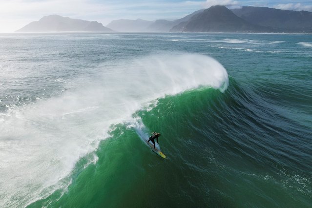 A drone view shows a surfer riding a wave at Sunset offshore reef as seasonal cold fronts drive big swells into the Cape Peninsula in Cape Town, South Africa on May 17, 2024. (Photo by Nic Bothma/Reuters)