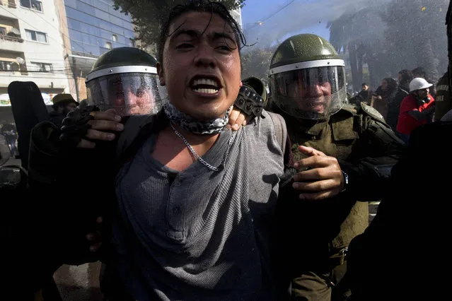 A man is detained by riot police during a protest turned violent near Congress, where President Michelle Bachelet was presenting the state-of-the-nation report, in Valparaiso, Chile, Saturday, May 21, 2016. (Photo by Esteban Felix/AP Photo)