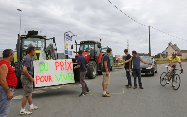 Livestock breeders block the entrance of a commercial center in Saint-Malo in the northwestern region of Brittany, France, to protest against a squeeze in margins by retailers and food processors, July 22, 2015. The placard reads “Fair prices to live”. (Photo by Jacky Naegelen/Reuters)