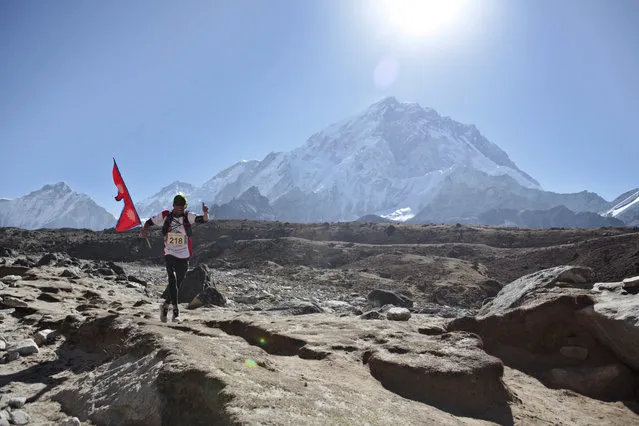 A Nepalese runs with his national flag during a marathon to mark the first conquest of Mount Everest, at Lobuche, near Everest base camp, Nepal, Monday, May 29, 2017. Nepal's mountaineering community is celebrating the first conquest of Everest and a successful climbing season in which hundreds of climbers scaled the world's highest peak. Monday is the 64th anniversary of the first successful climb of Everest by New Zealander Edmund Hillary and his Sherpa guide Tenzing Norgay. (Photo by Tashi Sherpa/AP Photo)