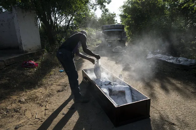 Cemetery worker Roberto Jesus Sangroni, known by his friends as “Makuka”, covers the body of Nerio Jesus Garcia with lime, moments after his autopsy to help reduce the smell, two days after his death as he prepares the body for a wake burial at the municipal cemetery in Cabimas, Venezuela, November 30, 2019. Garcia's mother found his corpse with a gun shot between his eyes on the bank of Maracaibo Lake following a phone call from a prisoner that her son had escaped from jail. (Photo by Rodrigo Abd/AP Photo)