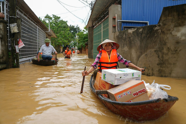 A woman rows a boat along a flooded street carrying packages of food in Thai Nguyen province on September 10, 2024, in the aftermath of Typhoon Yagi hitting northern Vietnam. Tens of thousands of people were forced to flee their homes on September 10 as massive floods inundated northern Vietnam in the wake of Typhoon Yagi, and the death toll climbed to 82. (Photo by Huu Hao/AFP Photo)