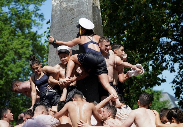 Plebes form a human pyramid to place an upperclassman hat atop the 21-foot vegetable shortening-covered Herndon Monument, a tradition marking the end of their plebe year at the U.S. Naval Academy in Annapolis, Maryland, U.S., May 23, 2022. (Photo by Kevin Lamarque/Reuters)
