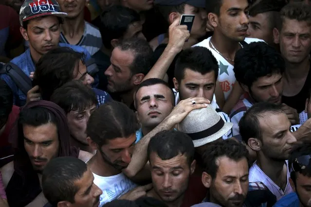 A Syrian refugee (C) tries to catch his breath as he stands in a crowded line to get registered in the national stadium of the Greek island of Kos, August 12, 2015. (Photo by Alkis Konstantinidis/Reuters)