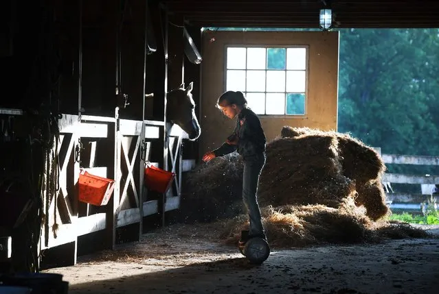 Makenna Goemmer, 11, rides a hoverboard in her family’s horse barn after practicing for a rodeo in Amissville, Va. on May 23, 2019. (Photo by Matt McClain/The Washington Post)