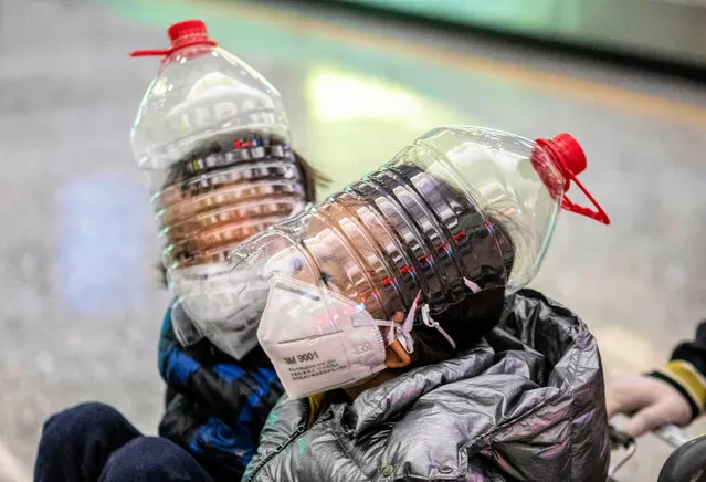 Childrean wear an improvised face protection made from water bottles in order to protect against the coronavirus at the airport arrival terminal in Guangzhou, Guangdong Province, China, 01 February 2020. Guangzhou Airport, usually busy during the end of Spring Festival when Chinese travelers return to their homes, appeared deserted after many countries and international airlines suspended or limited flights to and from China, because of outbreak of coronavirus in Wuhan City. (Photo by Alex Plavevski/EPA/EFE)