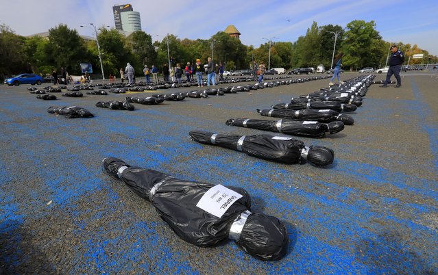 153 plastic covered mannequins, bearing labels with fictive names, ages and jobs, lay on the ground during a protest on government health policies regarding cancer affected patients held in front of the government headquarters in Bucharest, Romania, 17 October 2023. The participants asked the government to unlock the National Plan to Fight Cancer and to access European Union funding for the fight against cancer, as 153 people die of cancer every day, according to the organizers. According to a 2022 report by the European Commission, 55,000 people die annually in Romania due to cancer. (Photo by Robert Ghement/EPA/EFE)